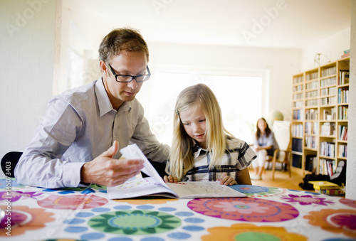 Father helping daughter with homework photo