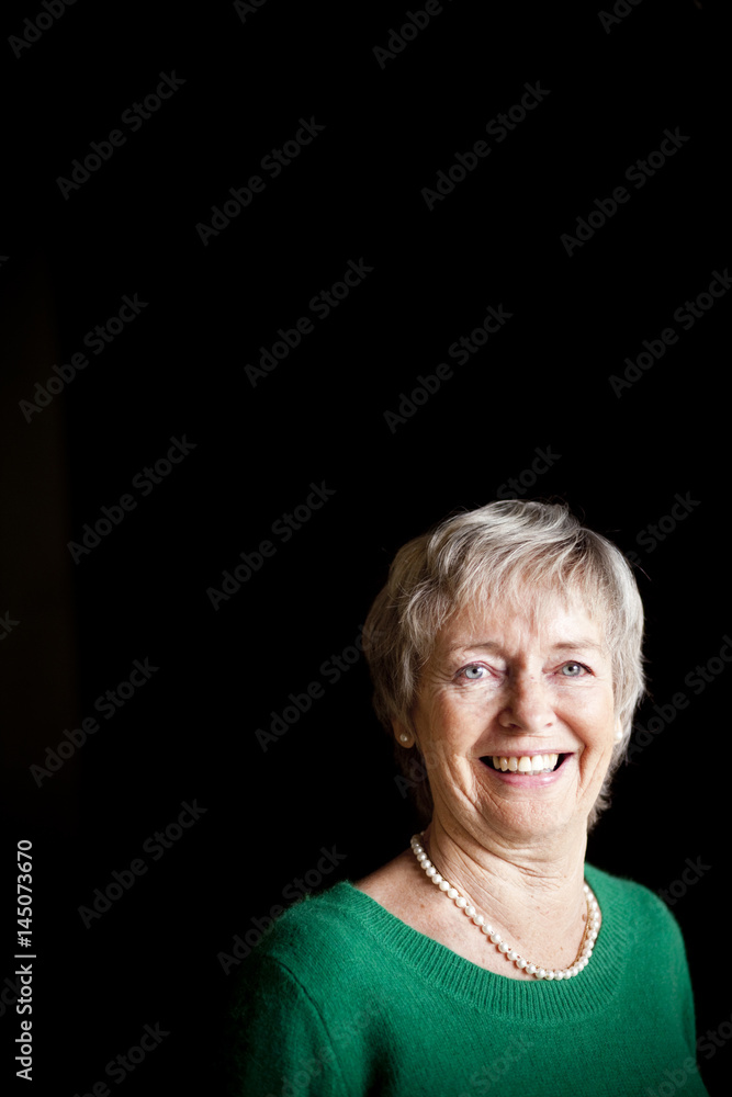 Portrait of cheerful senior woman against black background Portrait of cheerful senior woman against black background