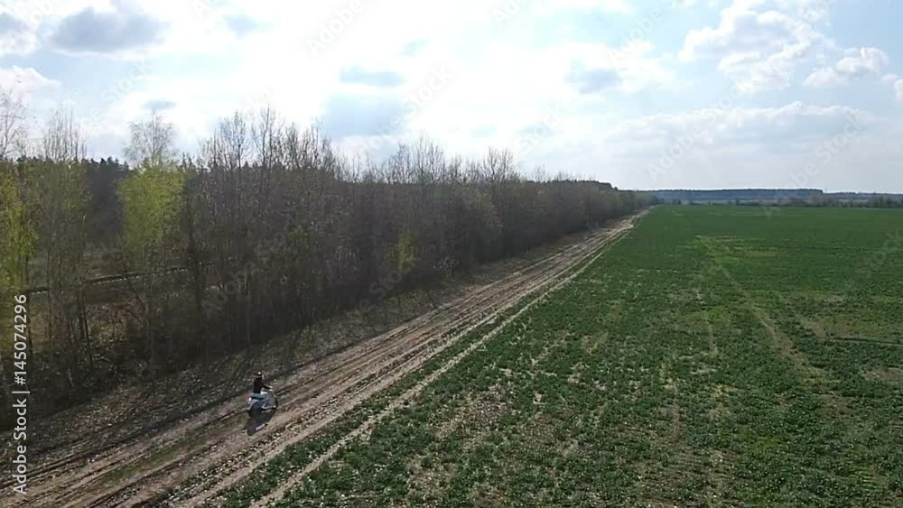A girl is riding a moped on an alley with trees