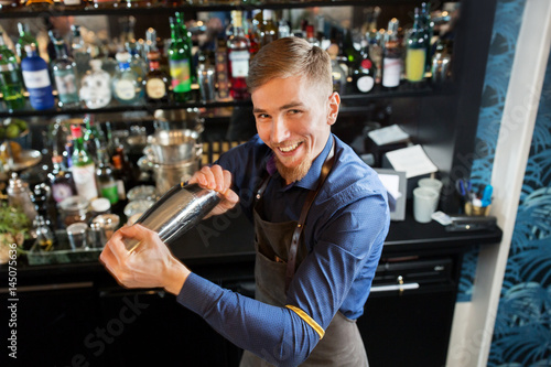 happy barman with shaker preparing cocktail at bar