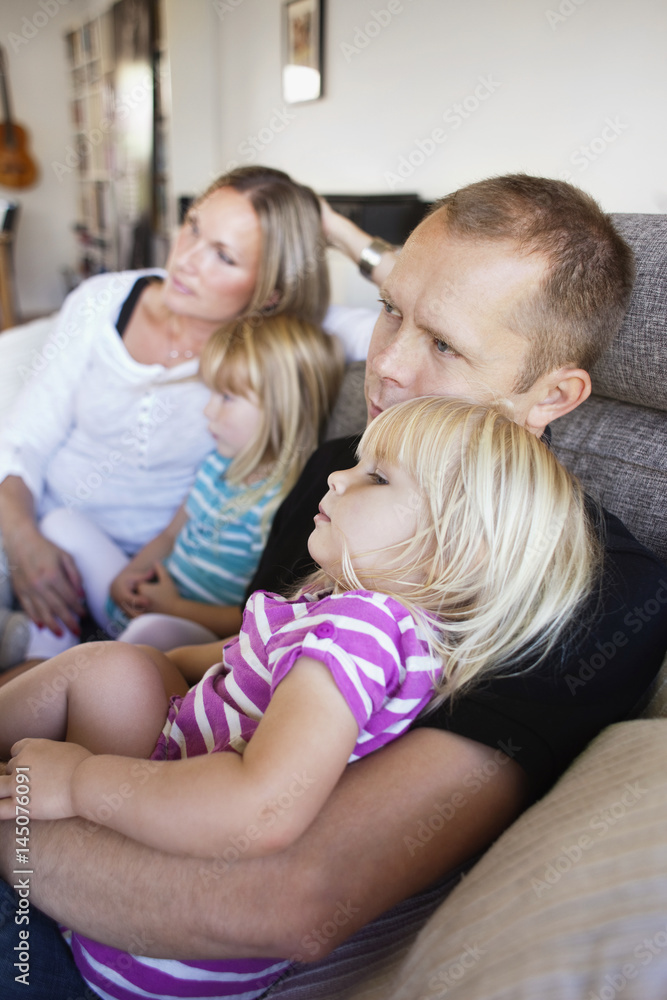 Family sitting on sofa in living room at home Family sitting on sofa in living room at home