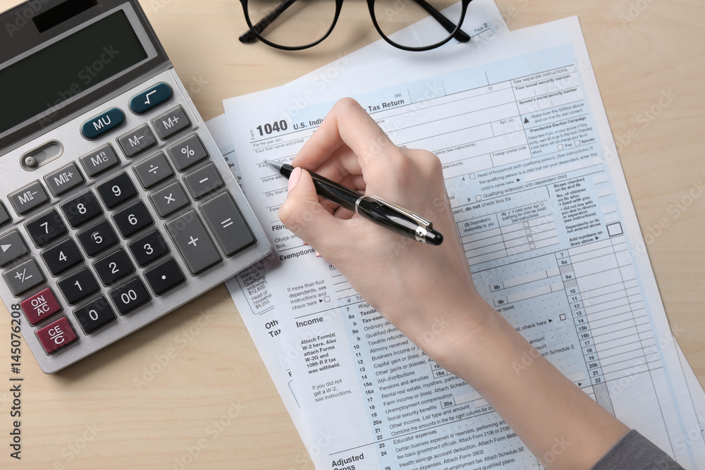 Woman filling in individual income tax form, closeup Woman filling in individual income tax form, closeup