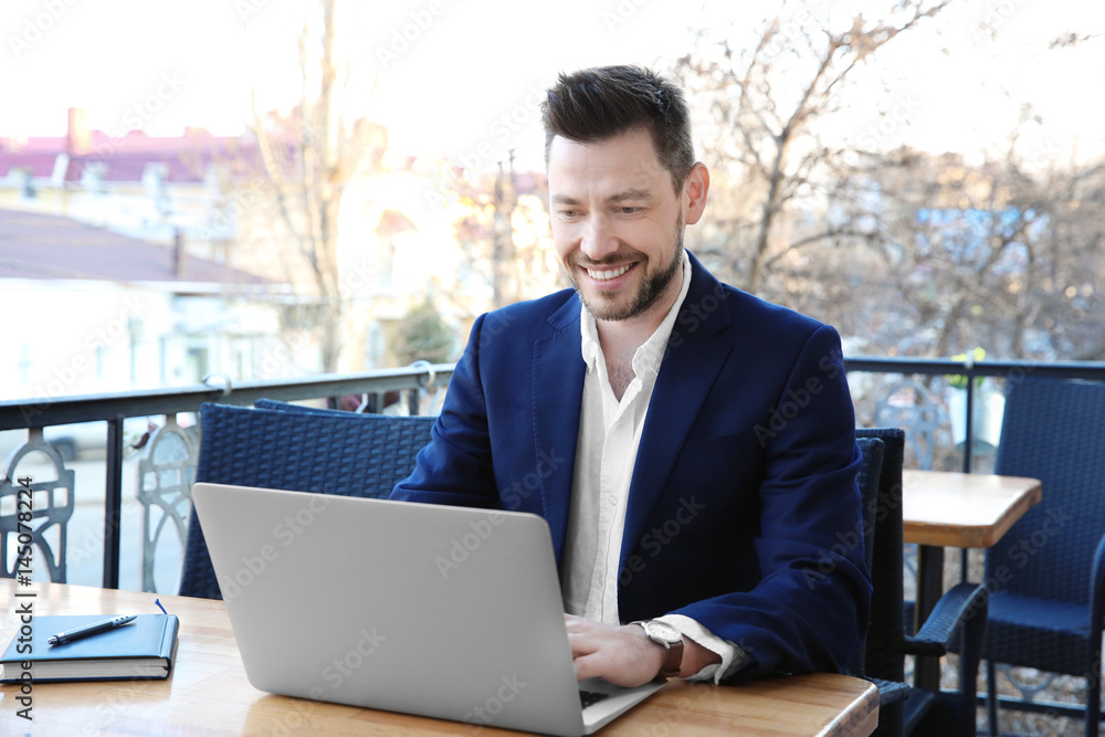 Young businessman working with laptop in outdoor cafe