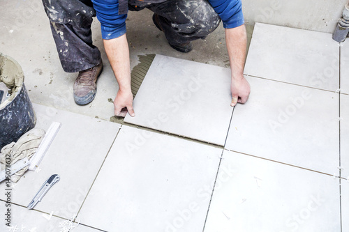 Tiling Floor & Wall. The tiler builder arranges the bathroom ceramics. Laying tiles on the floor