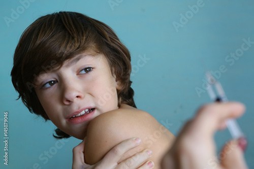 teenager boy in doctors cabinet undergo vaccination afraid photo