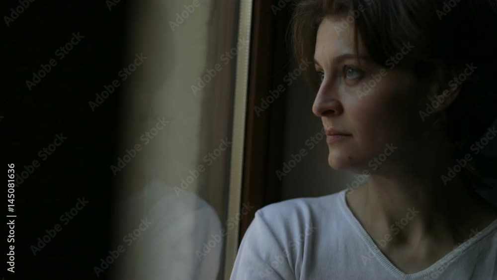 Sad female looking out the window,and think about something, broken-hearted Sad female looking out the window,and think about something, broken-hearted
