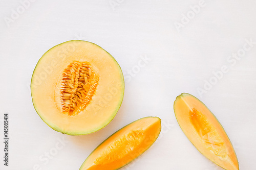 Ripe melon half and slices on white background, top view, blank space