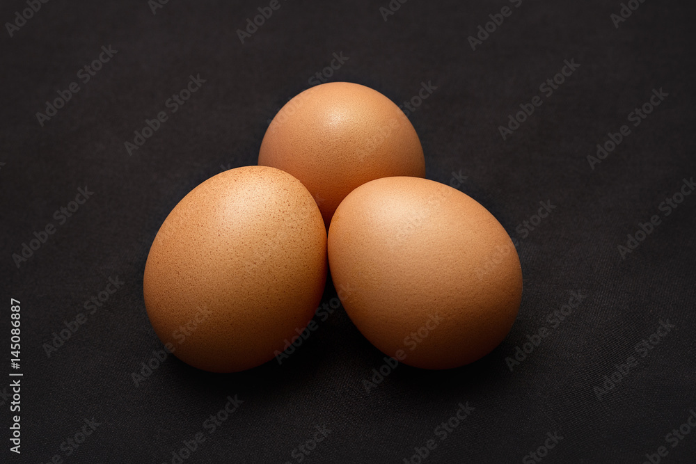 Three chicken eggs on a black background. Close up Three chicken eggs on a black background. Close up