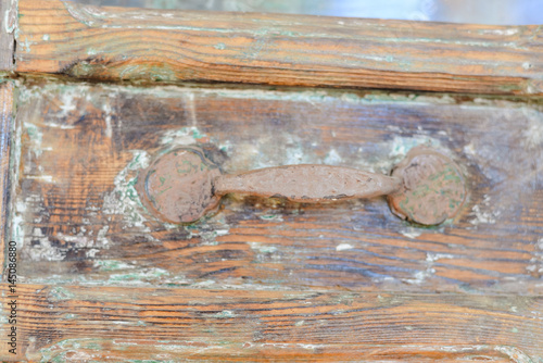 Closeup on old wooden entrance door with decorative antique door handle, selective focus, background blurry photo