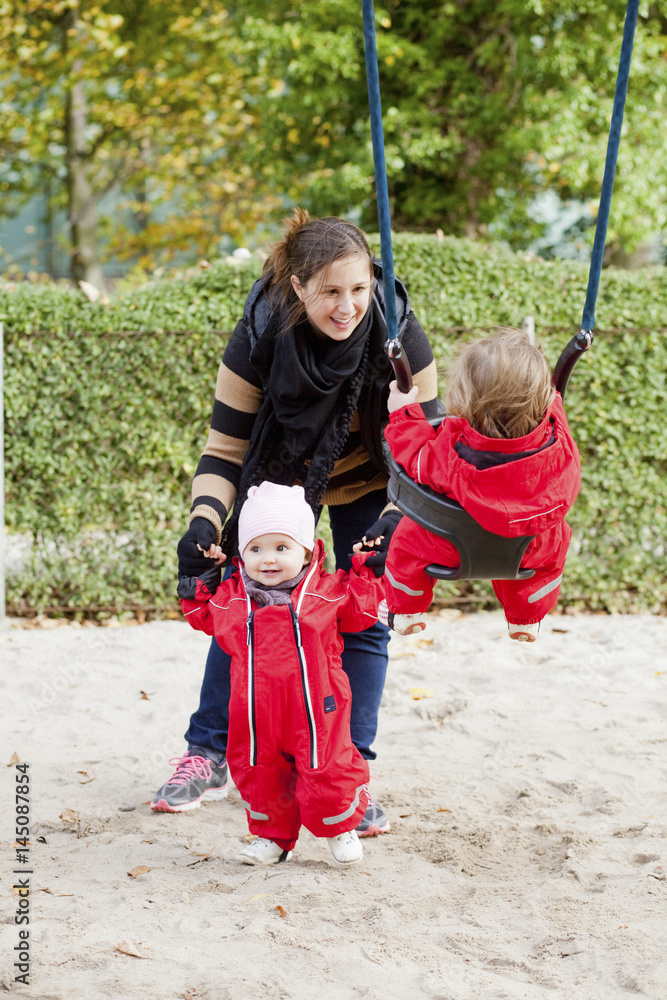 Happy woman with daughters enjoying at playground in park Happy woman with daughters enjoying at playground in park