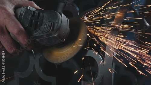 Wallpaper Mural Decorative metalworking: the creation of an openwork decorative metal element. Back plan: the worker's arm holds an angle grinder with a circular cutting blade. The power tool is in operation. Torontodigital.ca