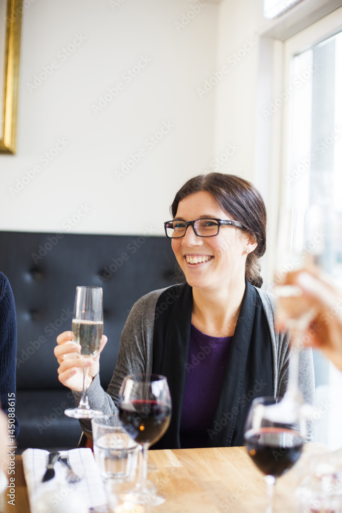 Happy woman looking away while holding champagne flute at restaurant table Happy woman looking away while holding champagne flute at restaurant table