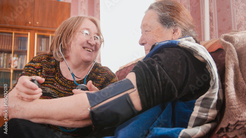 Two pensioners - senior ladies have fun - checking health state with manometer - measures pressure, pensioners healthcare photo