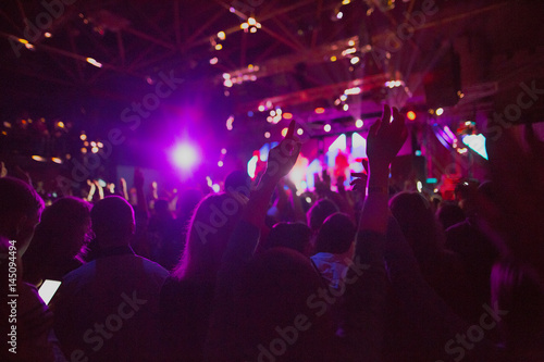 The silhouettes of concert crowd in front of bright stage lights