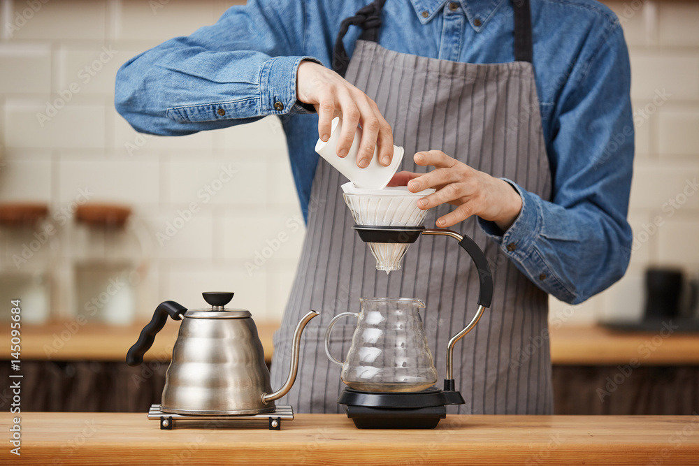 Closeup of male barista pouring ground coffee making pourover. Closeup of male barista pouring ground coffee making pourover.