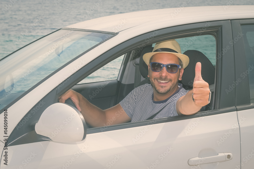Naklejka premium Portrait of tourist car driver showing thumbs up. Travel and summertime concepts. 