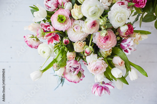  Flower arrangement with tulips and ranunculus on a white wooden floor. Spring flower 