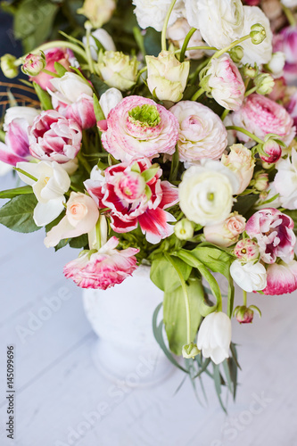  Flower arrangement with tulips and ranunculus on a white wooden floor. Spring flower 