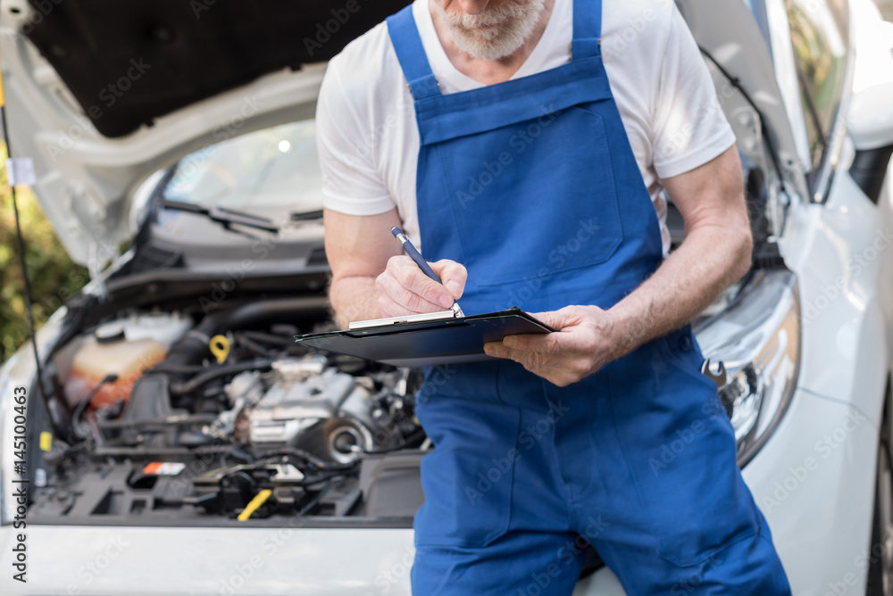 Car mechanic checking a car engine Car mechanic checking a car engine
