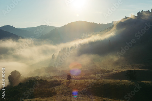 Landscape of the morning misty mountains. The magic place of the earth. Altai. Glare of the sun.