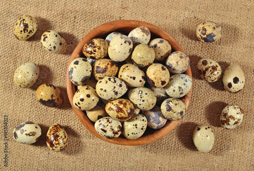 Quail eggs in a wooden bowl in a sacking
