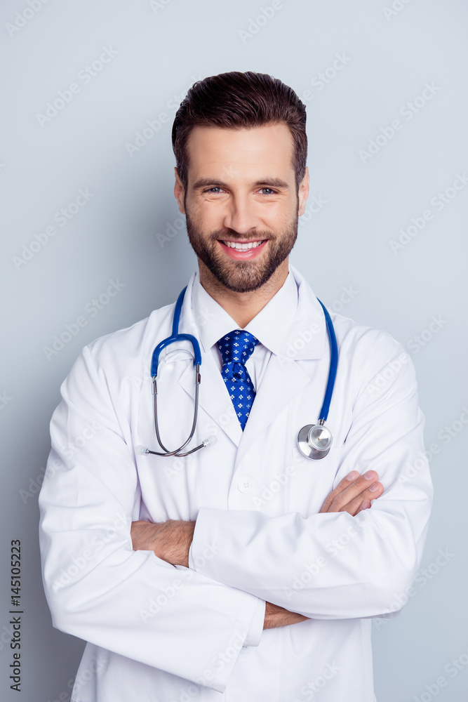 Vertical photo of cheerful smiling doc standing with crossed hands against gray background Vertical photo of cheerful smiling doc standing with crossed hands against gray background
