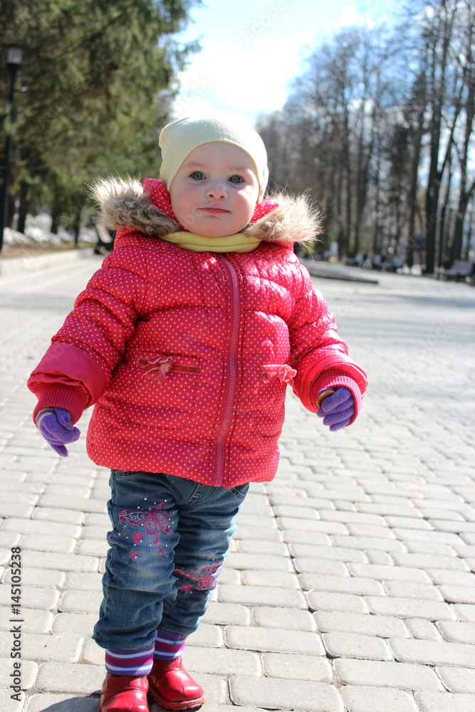 A girl walks down the street in spring and winter in a pink jacket smiles A girl walks down the street in spring and winter in a pink jacket smiles