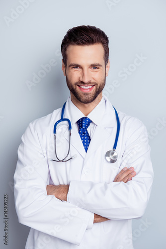 Vertical photo of cheerful smiling doc standing with crossed hands against gray background