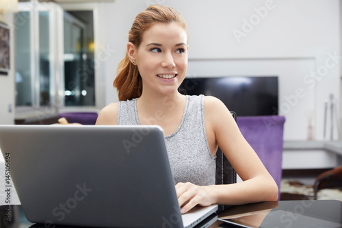 Cute woman using her notebook in her kitchen