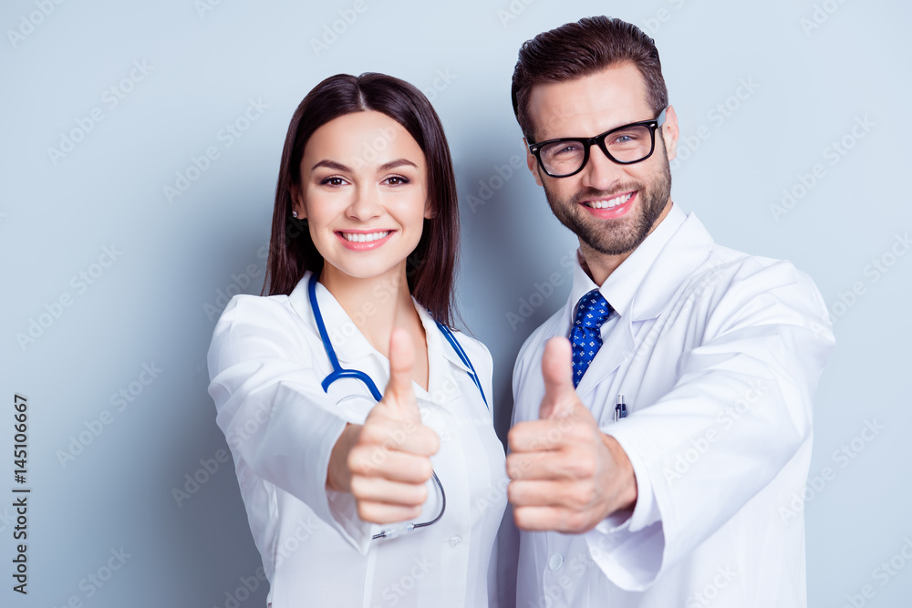 Happy medic workers. Portrait of two doctors in white coats and glasses showing thumb-up against white background Happy medic workers. Portrait of two doctors in white coats and glasses showing thumb-up against white background