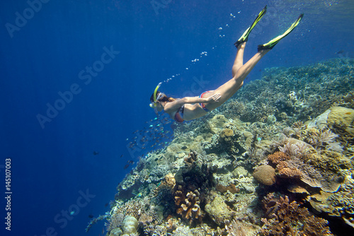woman snorkeling in tropical water near coral reef