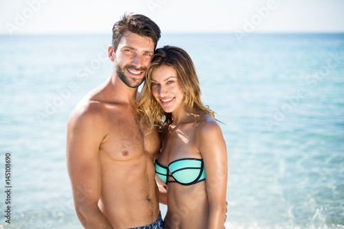 Young couple standing with arm around on shore at beach