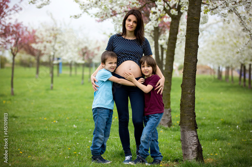 Pregnant woman and her two children in a spring blooming park