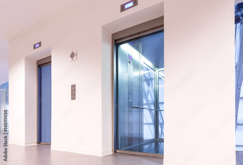Fototapeta premium Two doors of elevators with transparent walls in modern business building