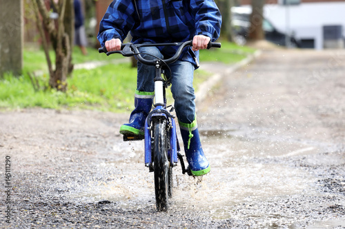 The boy on the bike riding on the puddles  