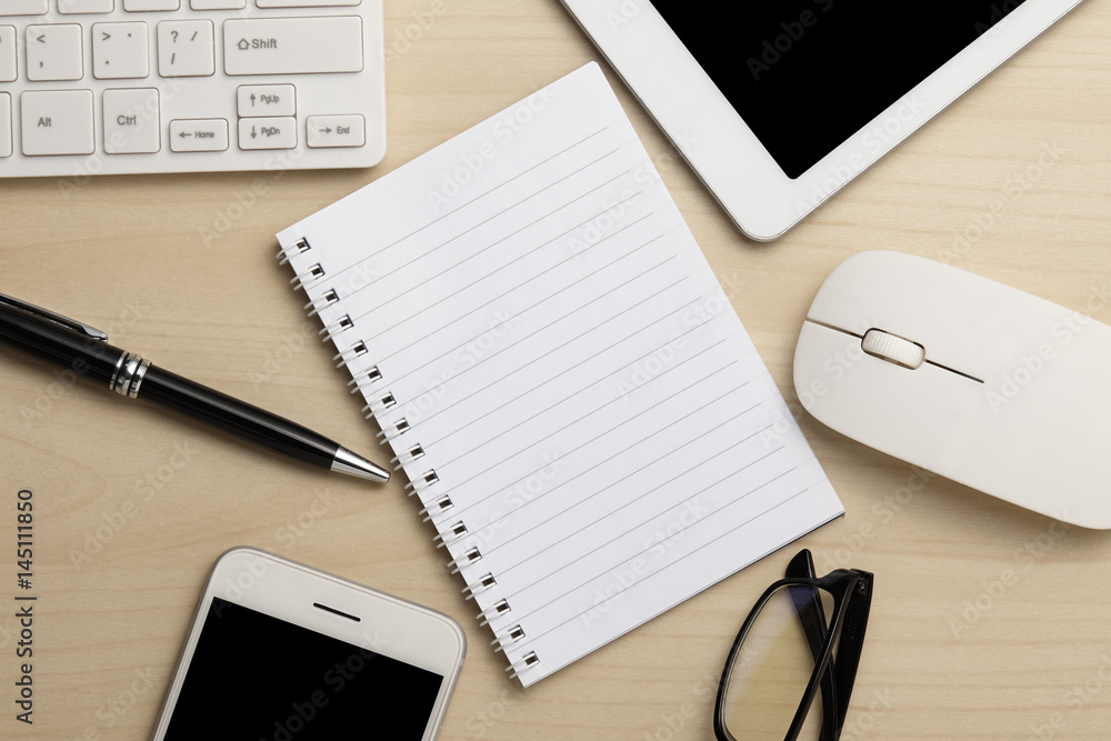 Modern working business desk with keyboard, notepad, smart phone, pen, mouse & glasses. Top view with copy space Modern working business desk with keyboard, notepad, smart phone, pen, mouse & glasses. Top view with copy space