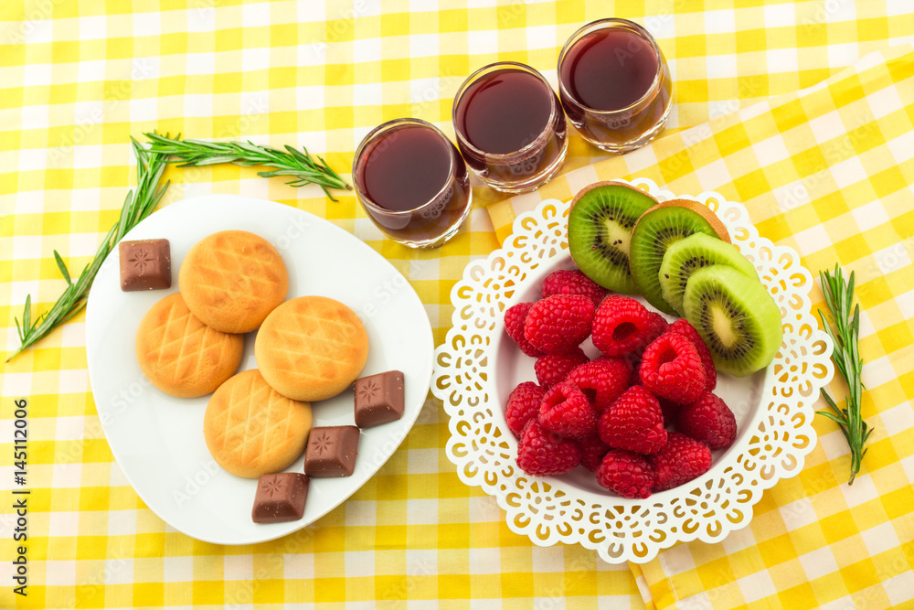 Fresh Red Raspberries on a white artistic plate / Red Fresh Raspberries on a white artistic plate with cookies, rosemary, chocolate and cream in the background. Fresh Red Raspberries on a white artistic plate / Red Fresh Raspberries on a white artistic plate with cookies, rosemary, chocolate and cream in the background.