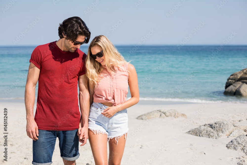 Couple wearing sunglasses while standing at beach