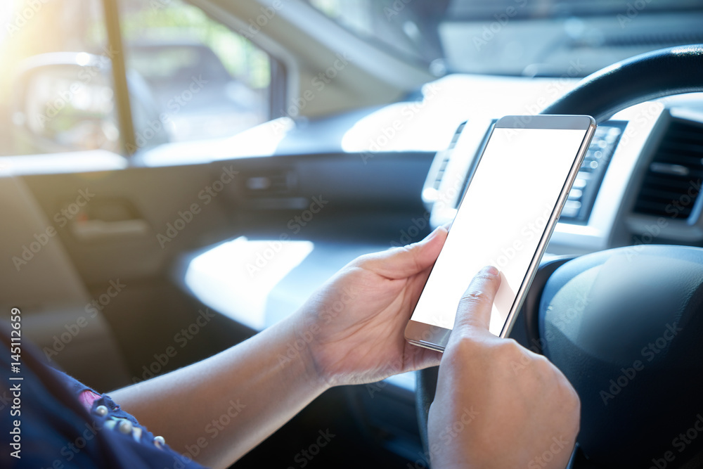 Woman driver using smart phone in car during traffic jam , blank white screen for design purpose . Woman driver using smart phone in car during traffic jam , blank white screen for design purpose .