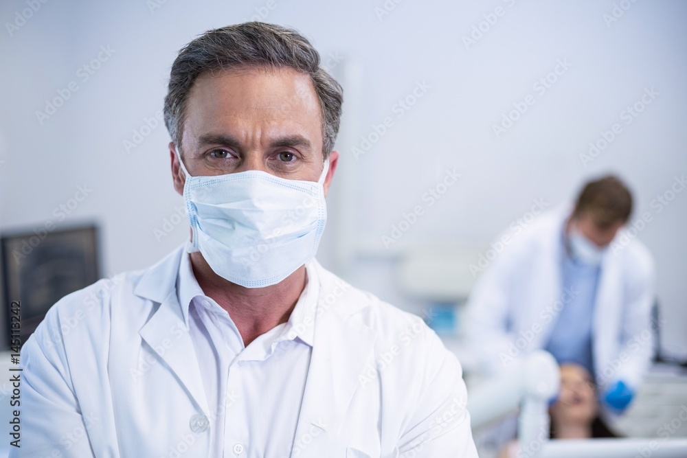Confident dentist in surgical mask at dental clinic