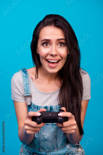 Vertical portrait of excited young cute woman using a console for playing computer game