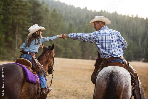 Cowboy and cowgirl on their horses photo