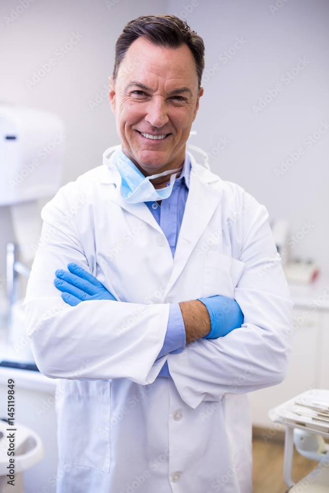Smiling dentist standing with arms crossed at dental clinic Smiling dentist standing with arms crossed at dental clinic