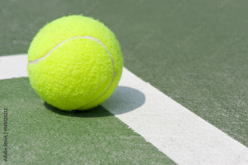 Close up of a yellow tennis ball on the corner line of the clay court with copy space and a shallow depth of field