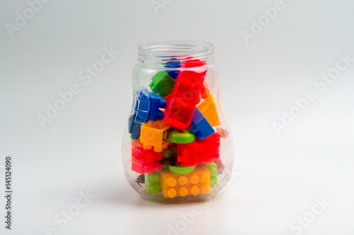 Multicolor plastic toy block in transparent plastic bottle isoltated on white background.