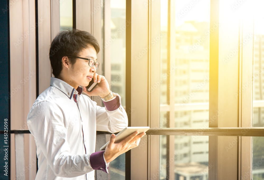 Handsome business man working with tablet and smart phone in office Handsome business man working with tablet and smart phone in office