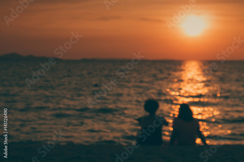 silhouette and blur of two middle-aged happy women sitting on the beach talking about old day and watching the sunset on the horizon. emotional and friend relation concept.  © gumpapa