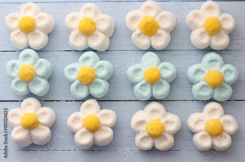 Fotografi White, blue and yellow daisy marshmallow sweets on duck egg blue painted table