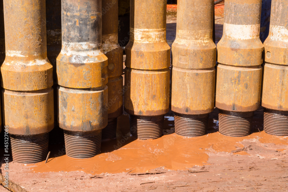 Drill pipe stands stacked on rig floor with mud spill Stock Photo