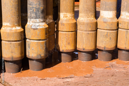 Drill pipe stands stacked on rig floor with mud spill
